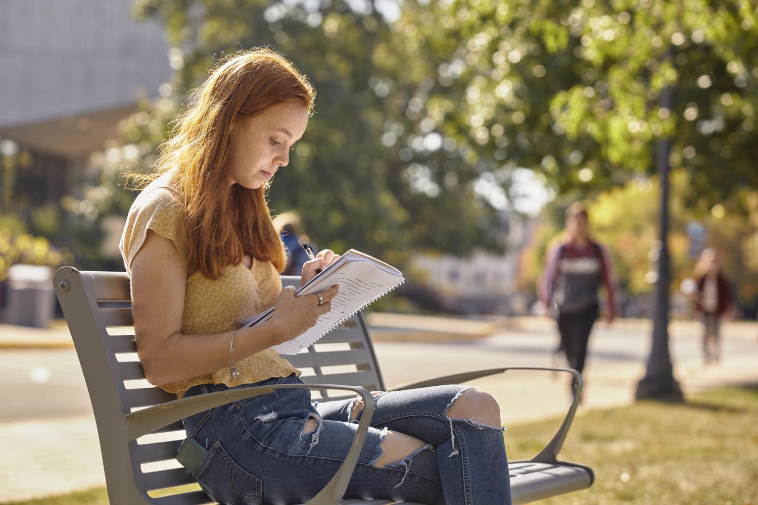 一位<a href='http://aktwif.fengxiangbia.com'>bv伟德ios下载</a>学院的学生在校园里的长椅上读书.